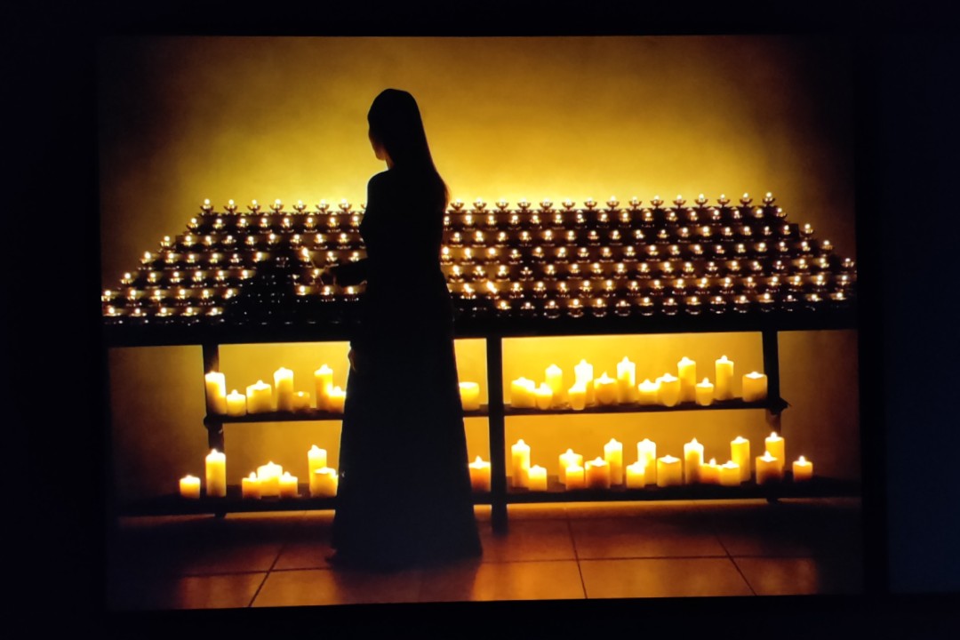 Bill Violan Yömessu, toinen osa kaksiosaisesta teoksesta. Nainen sytyttää kynttilöitä kirkossa